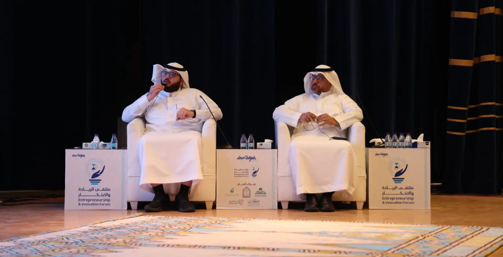 Two speakers on a panel stage at the Abha Chamber of Commerce